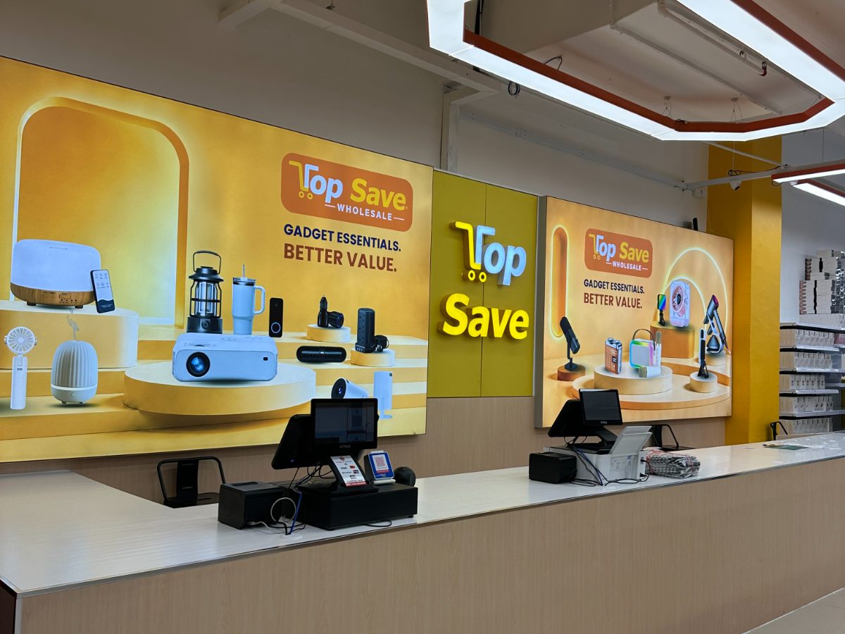 Gadget and electronics display counter beneath the Top Save Wholesale branded wall