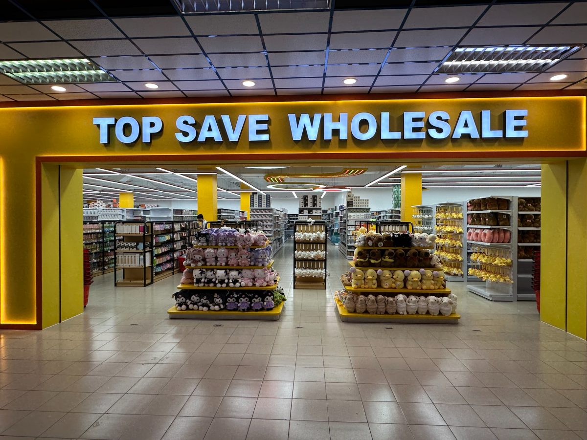 Illuminated TOP SAVE WHOLESALE sign above displays of plush toys
